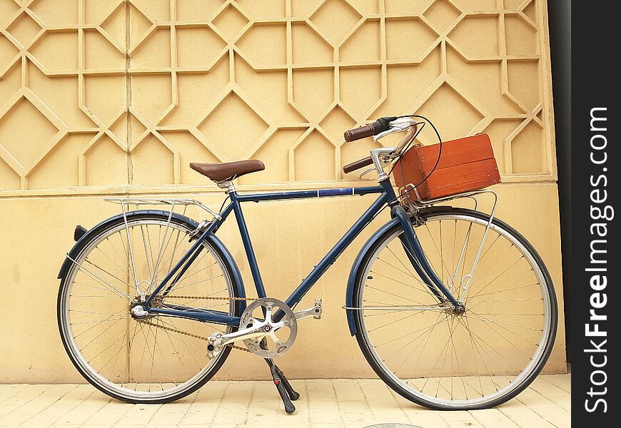 Beautiful retro bicycle set against a wall and equipped with a wooden box to carry stuff, ecological background.