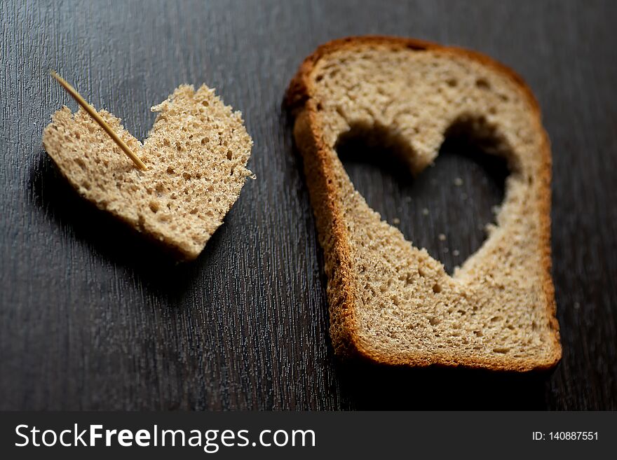 Hearts carved from a piece of bread on a dark wooden table