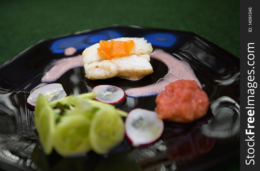 Fish plate gourmet with nice presentation on a black plate.