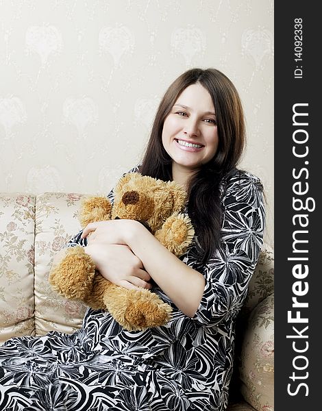 The image of a beautiful pregnant woman sitting on a vintage couch