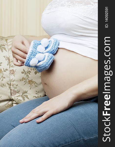 Pregnant Woman On The Couch With Blue Booties