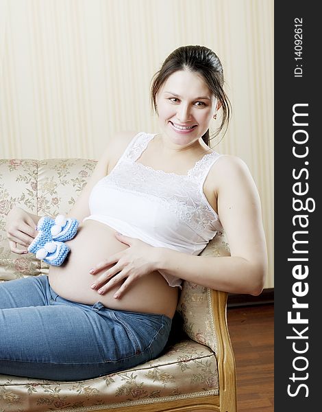 The image of a beautiful pregnant woman sitting on a vintage couch