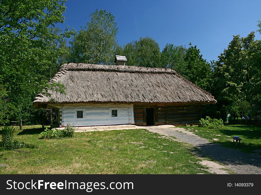 A small house with a thatched roof around a lot of green trees. A small house with a thatched roof around a lot of green trees