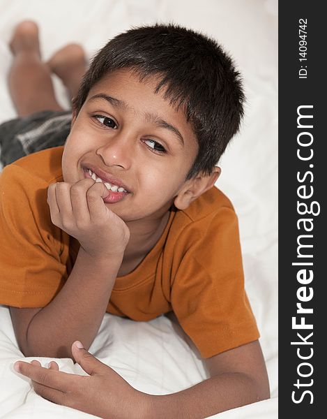 Handsome Indian kid lying happily on the bed. Handsome Indian kid lying happily on the bed