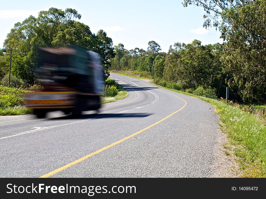 Car coming around a bend on the highway at a fast speed. Car coming around a bend on the highway at a fast speed.