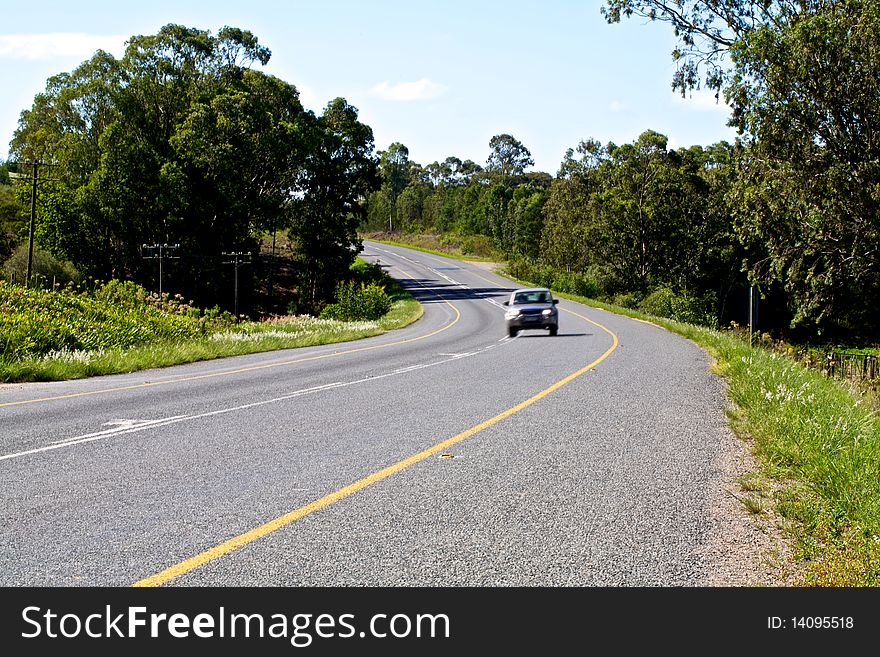 Car coming around a bend on the highway at a fast speed. Car coming around a bend on the highway at a fast speed.