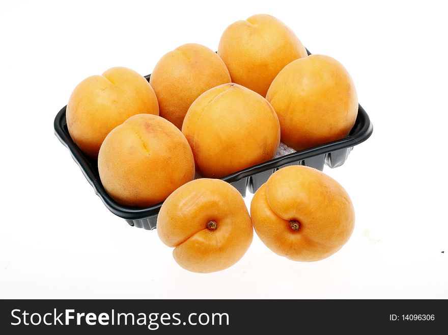 Some ripe apricot with the dark plastic box.(on white background.)