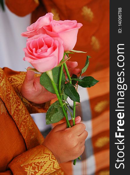 A kid is holding roses during a wedding ceremony. A kid is holding roses during a wedding ceremony