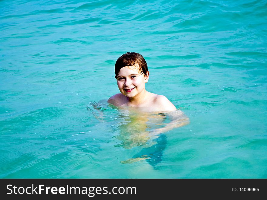 Smiling boy enjoys swimming  in the sea