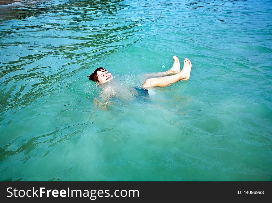 Young happy boy with brown hair enjoys swimming and jumping in the beautiful sea. Young happy boy with brown hair enjoys swimming and jumping in the beautiful sea