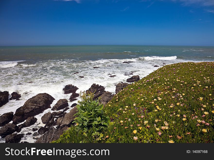 Scenic view of waves breading on rocky ocean coastline under blue skies. Scenic view of waves breading on rocky ocean coastline under blue skies.