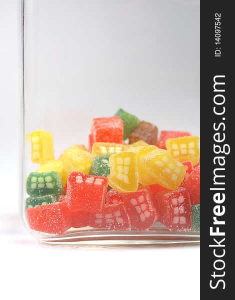 Delicious sweet candies in sugar in a glass jar. white background. copy-space