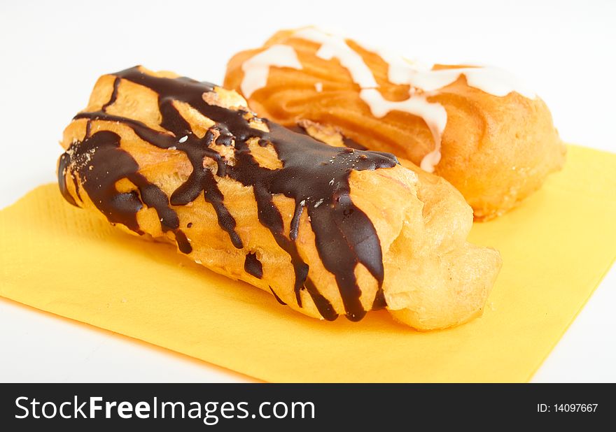 Two pastries filled with custard on yellow serviette on white background