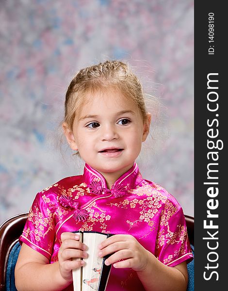 Portrait of a pretty little blond headed girl smiling and holding folding fan. Portrait of a pretty little blond headed girl smiling and holding folding fan.