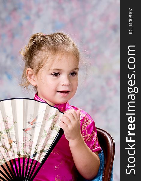 Portrait of a pretty little blond headed girl smiling and holding folding fan. Portrait of a pretty little blond headed girl smiling and holding folding fan.