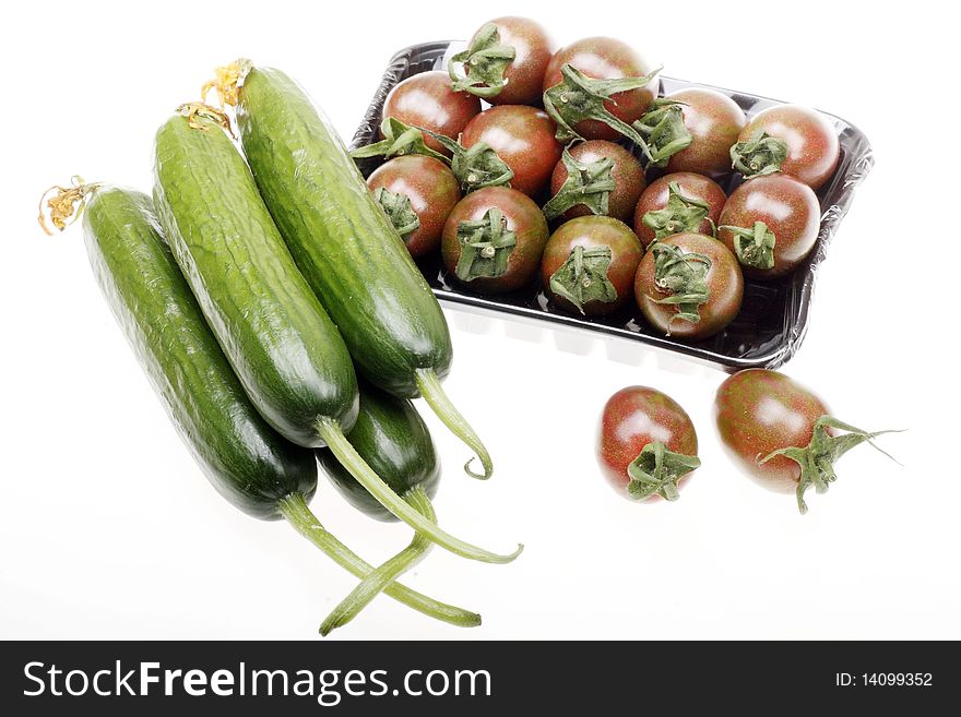 Fresh brown cherry tomatoes with cucumbers on white.