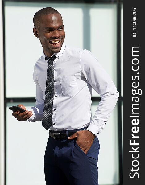 Portrait of happy african american businessman walking with cellphone