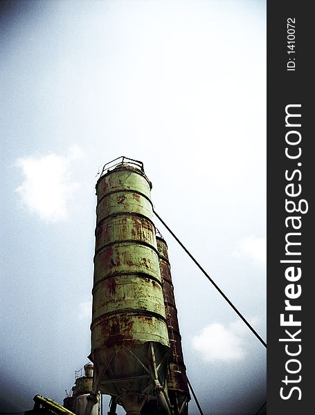 Tall abandoned rusty silo over blue sky in a dramatic rendition with vignette. Film-scan. Tall abandoned rusty silo over blue sky in a dramatic rendition with vignette. Film-scan.