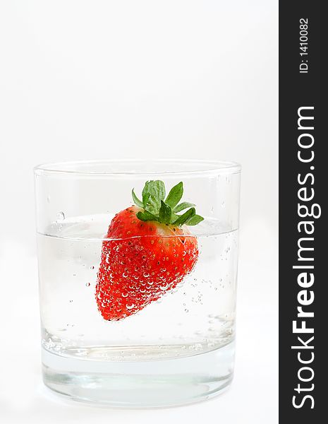 A strawberry into glass with mineral water.