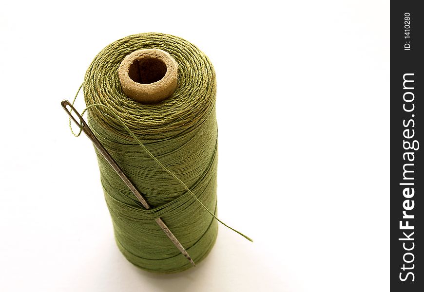 Reel of green cotton with threaded needle. Reel of green cotton with threaded needle