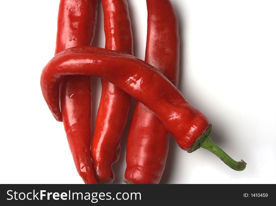 Four red hot chilli peppers closeup on a white background