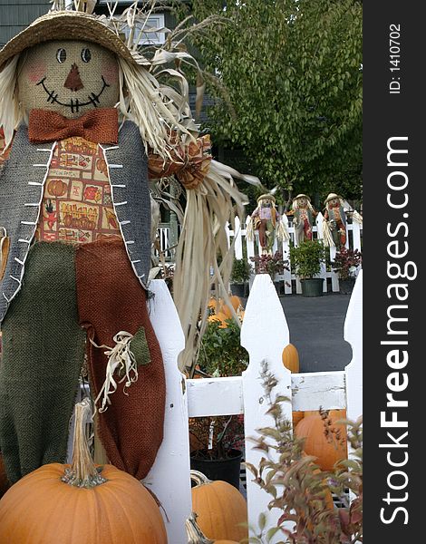 Scarecrow on white picket fence.