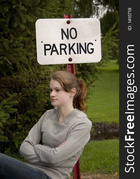 Attractive teen leaning up against a No Parking sign. Attractive teen leaning up against a No Parking sign.