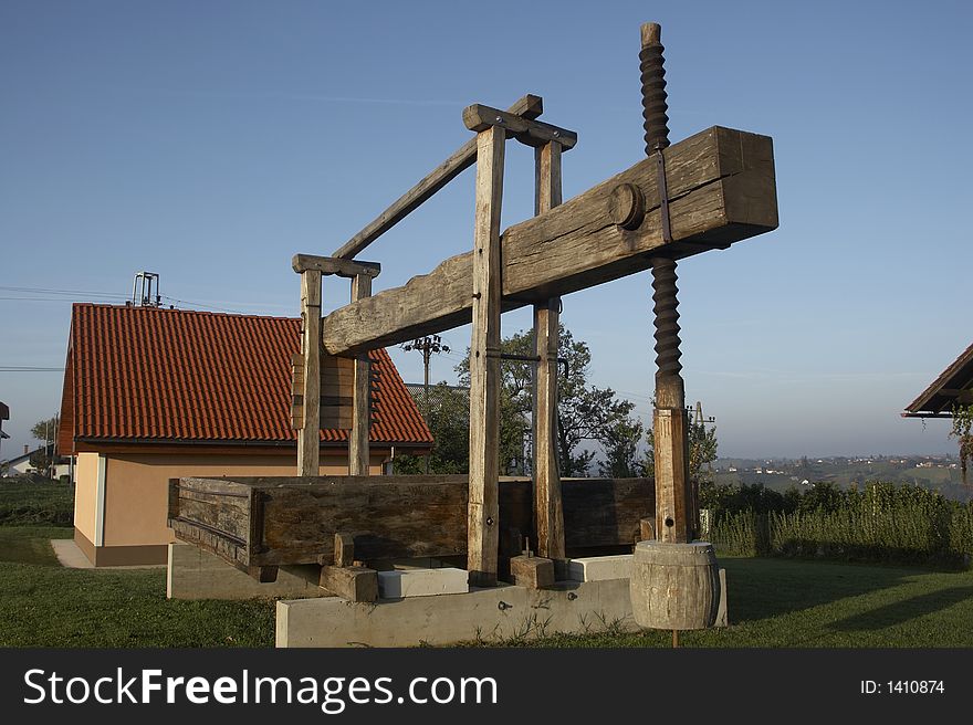 Vintage wine press against blue sky.