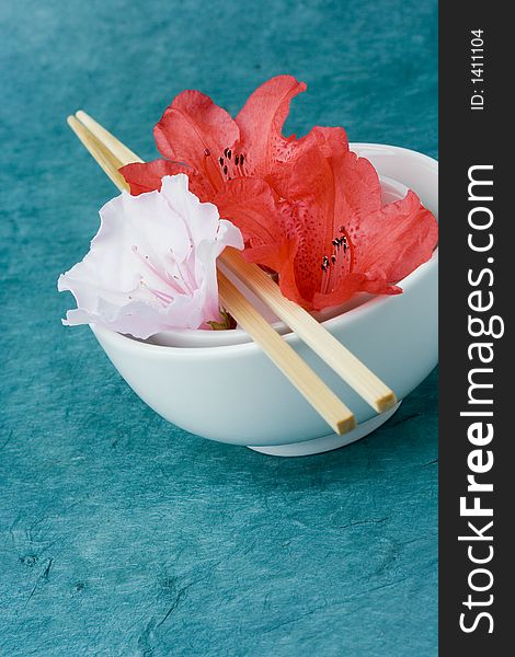 Azaleas or Rhododendron flowers positioned in two rice bowls with chop sticks. Conceptual representation of presentation, styling, food and freshness. Azaleas or Rhododendron flowers positioned in two rice bowls with chop sticks. Conceptual representation of presentation, styling, food and freshness.