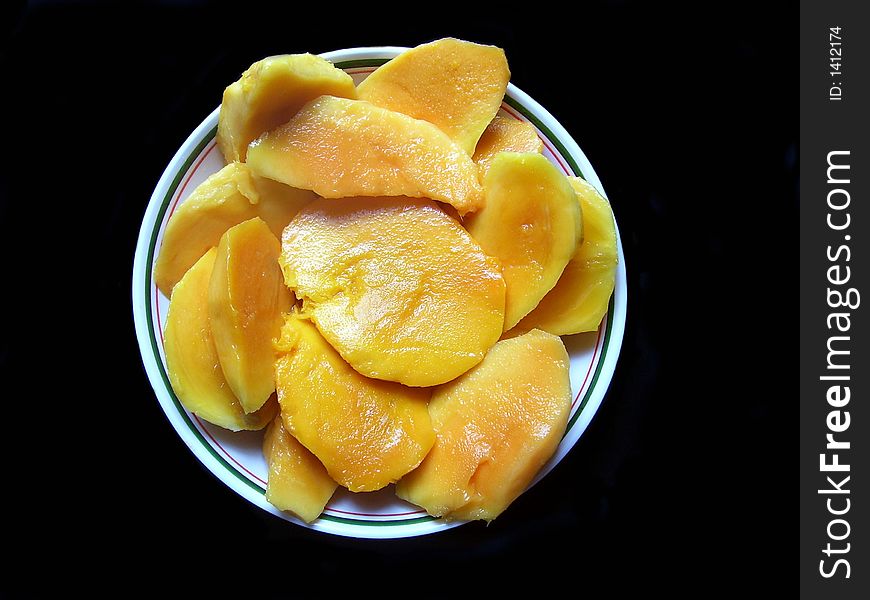 Juicy mango slices over black background