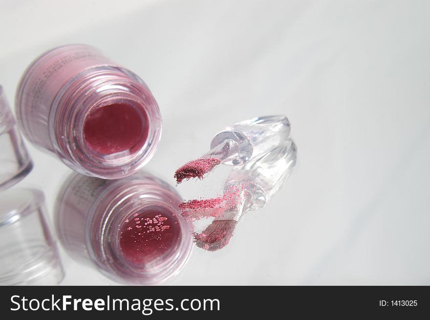 A pot of pink powder spilling onto a reflective surface. A pot of pink powder spilling onto a reflective surface.