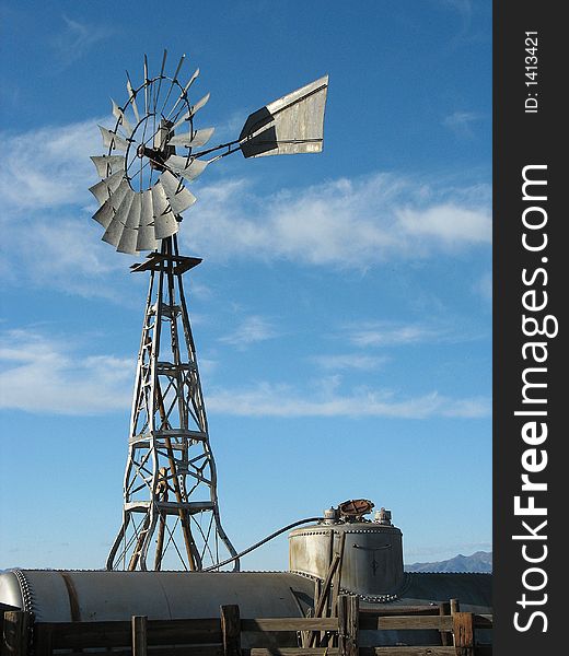 A windmill made out of old car frames pumps water into an old railroad tank car for storage. A windmill made out of old car frames pumps water into an old railroad tank car for storage.