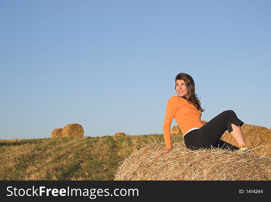 Beautiful woman in a field with hay bales