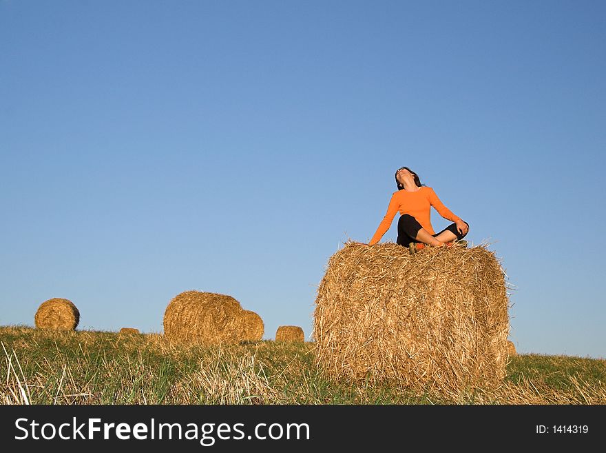 Beautiful woman seated in hay bale