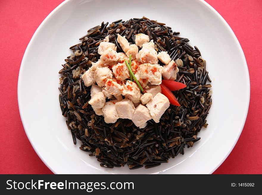 Black rice with boiled chicken breast on a white plate. Black rice with boiled chicken breast on a white plate.