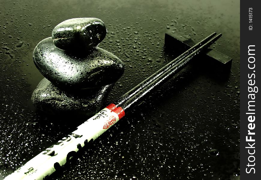 Hot stones on black whit chopsticks and water drops. Hot stones on black whit chopsticks and water drops