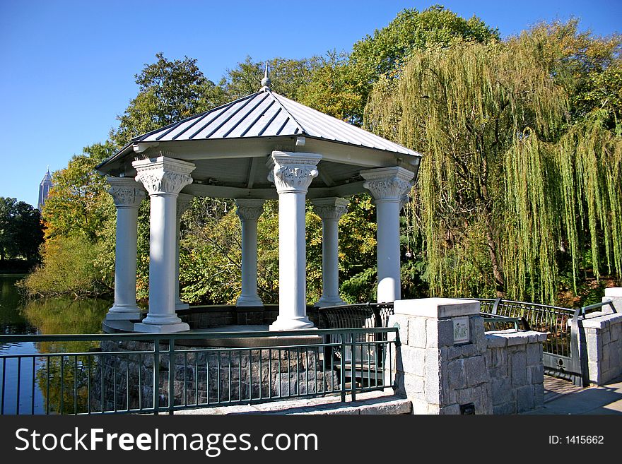 White gazebo next to lake in city park. White gazebo next to lake in city park