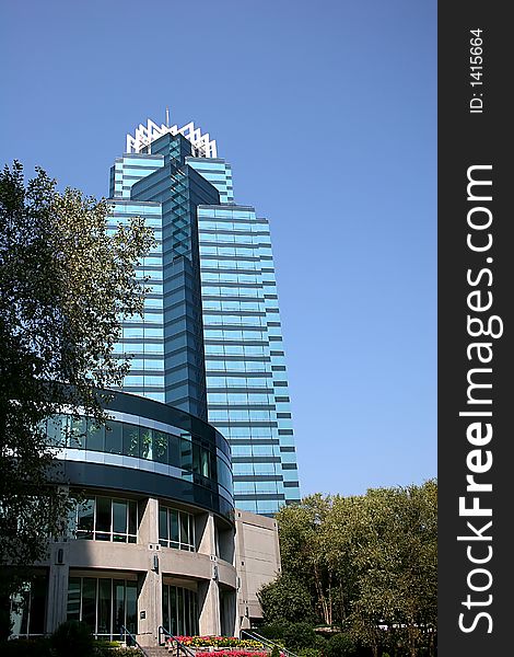 Blue office tower adjacent to shorter office building against blue sky. Blue office tower adjacent to shorter office building against blue sky