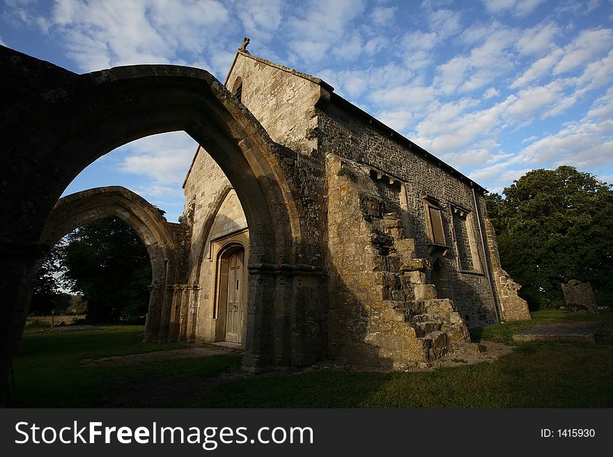 A beautiful ruined but still consecrated church in England under late afternoon sunlight and a blue sky with some clouds. A beautiful ruined but still consecrated church in England under late afternoon sunlight and a blue sky with some clouds