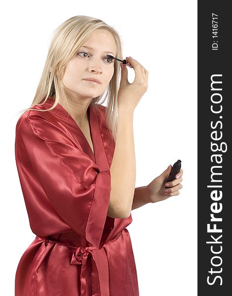 Young woman dressed red bathrobe putting mascara