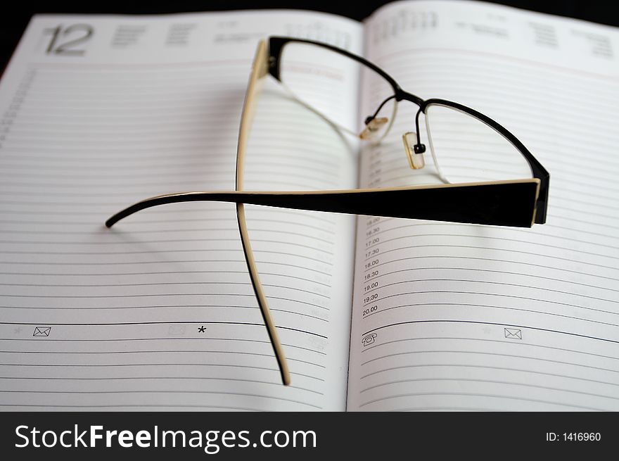 Eyeglasses on notebook on black