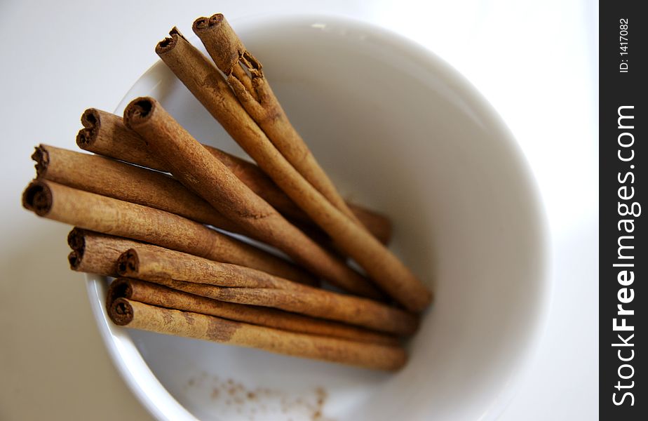 Cinnamon sticks in a white bowl on white table