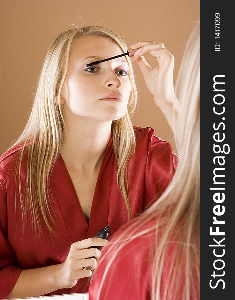 Reflexion of young blone woman putting mascara