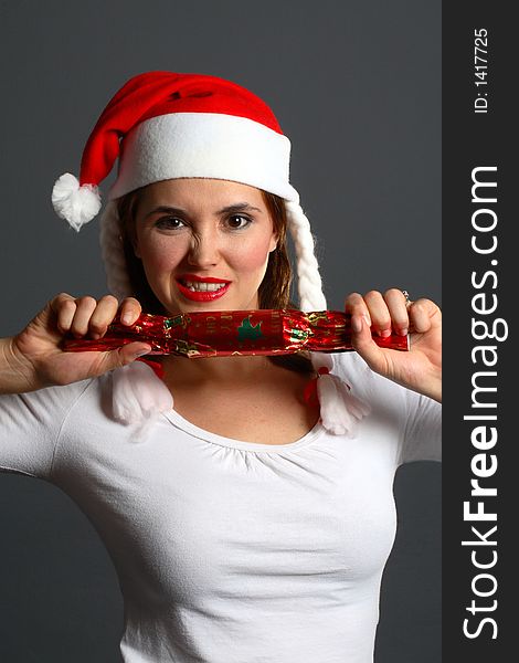 Brunette wearing a santa hat pulling on Christmas cracker. Brunette wearing a santa hat pulling on Christmas cracker