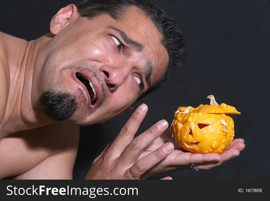 Portrait of a man scared of little halloween pumpkin