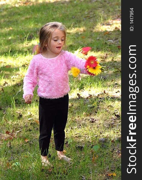 A little girl standing by a tree barefoot holding a bouquet of daisies she just picked from the garden. A little girl standing by a tree barefoot holding a bouquet of daisies she just picked from the garden.