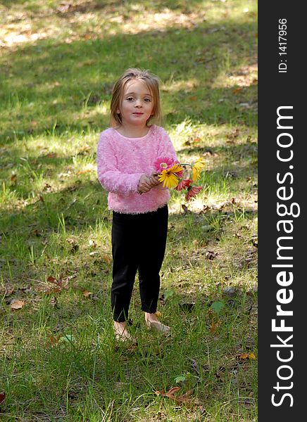 A little girl standing by a tree barefoot holding a bouquet of daisies she just picked from the garden. A little girl standing by a tree barefoot holding a bouquet of daisies she just picked from the garden.