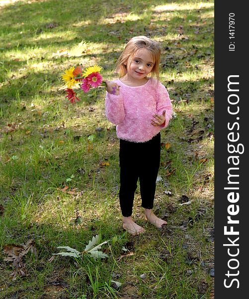 A little girl standing barefoot holding a bouquet of daisies she just picked from the garden. A little girl standing barefoot holding a bouquet of daisies she just picked from the garden.