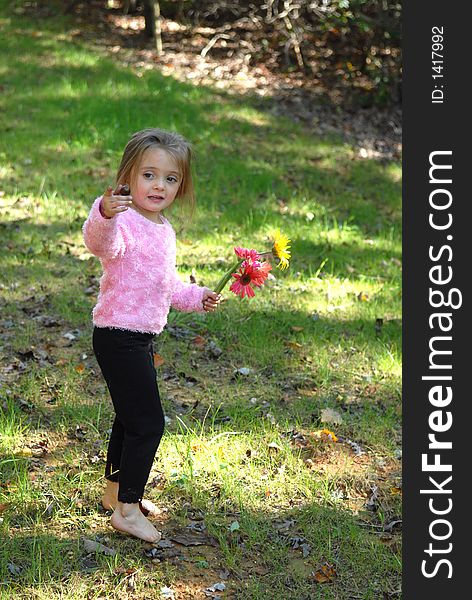 A little girl  holding a bouquet of daisies in one hand and a walnut in the other. A little girl  holding a bouquet of daisies in one hand and a walnut in the other