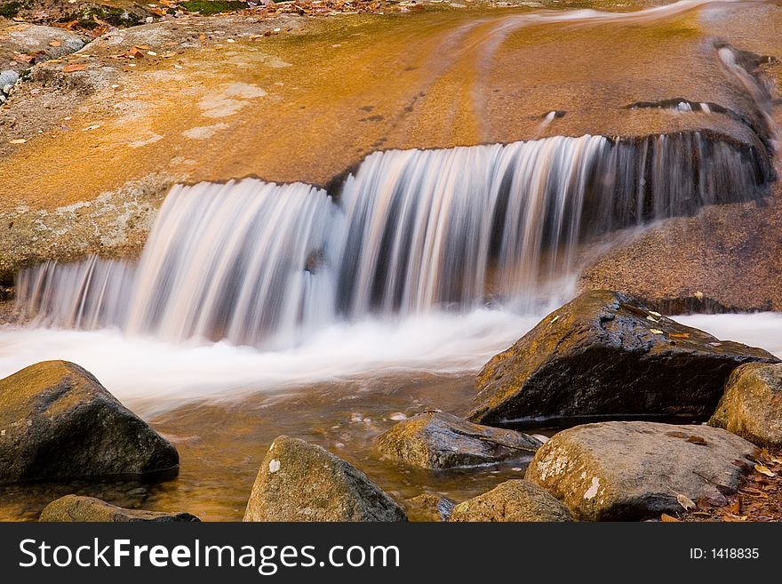 Autumn stream flows over smooth brown rocks. Autumn stream flows over smooth brown rocks.